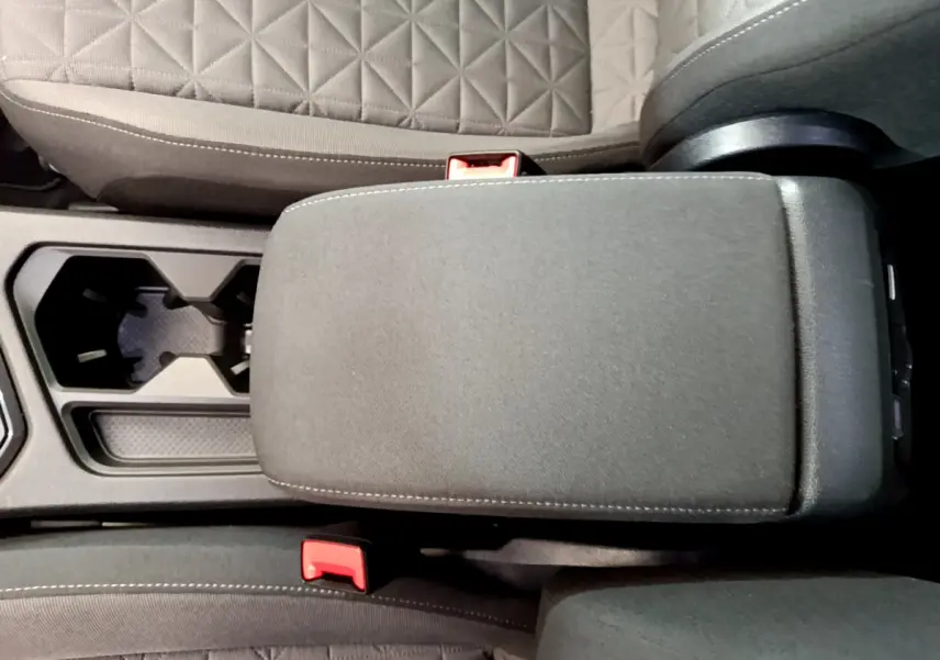 Vue rapprochée de l'accoudoir central noir et des sièges tissu gris du Volkswagen Tiguan 2021 intérieur.