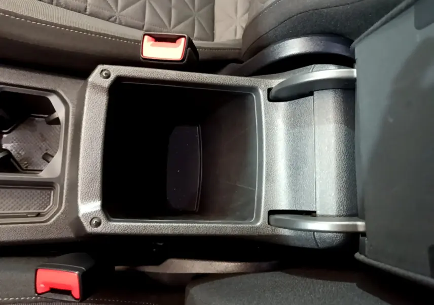 Vue plongeante sur la console centrale noire du Volkswagen Tiguan 2.0 TDI avec accoudoir ouvert et sièges gris à surpiqûres.