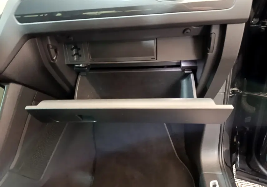 Gant de rangement ouvert côté passager dans l'habitacle noir du Volkswagen Tiguan 2021.