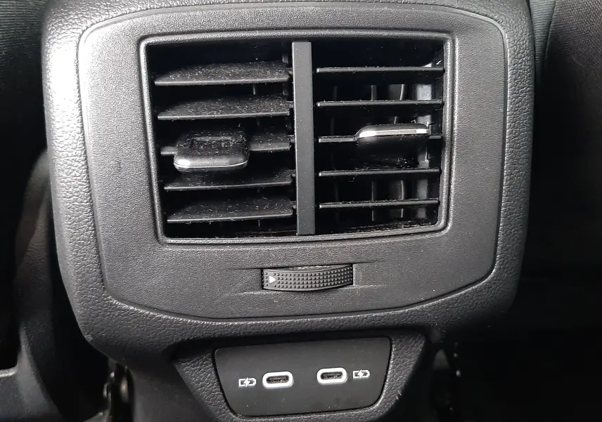 Vue plongeante sur la console centrale noire du Volkswagen T-Roc 2023, avec porte-gobelets et ceintures rouges visibles.