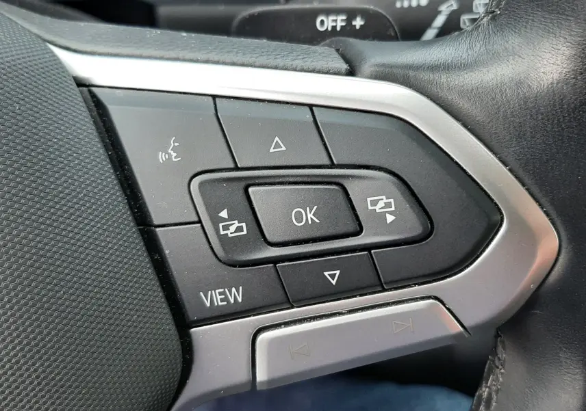 Gros plan sur les commandes de régulateur de vitesse au volant du Volkswagen T-Roc 2023, intérieur noir.