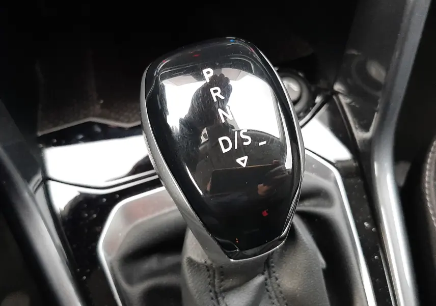 Gros plan sur la console centrale noire du Volkswagen T-Roc 2023 avec porte-gobelets et boutons de frein à main électronique.