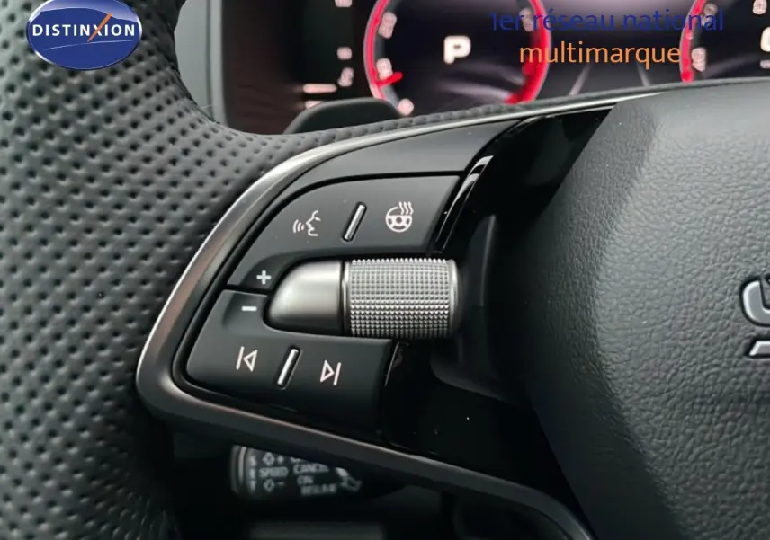 Gros plan sur les commandes du volant du Skoda Karoq gris argent 2025, avec molette et boutons multifonctions.