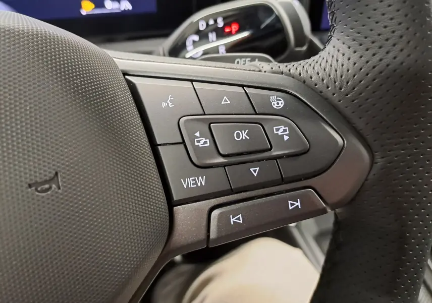 Gros plan sur les commandes au volant du Volkswagen T-Roc 2026, boutons multifonctions avec finition noire et cuir perforé.