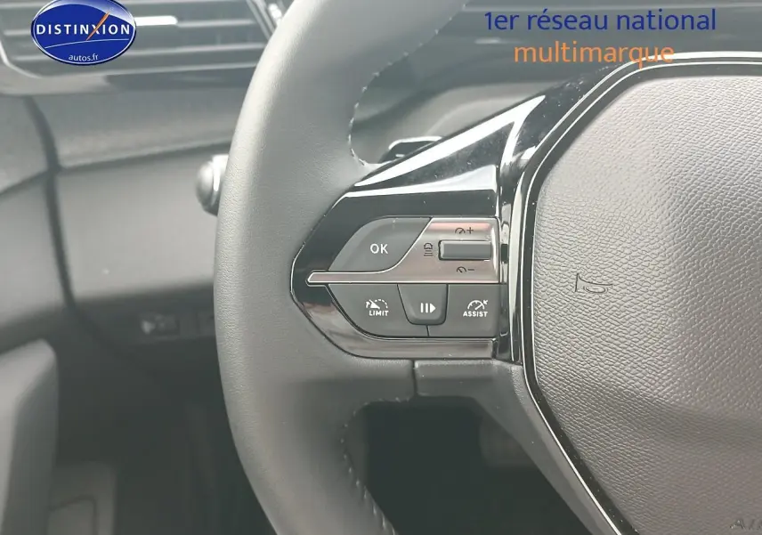 Gros plan sur le volant multifonction noir côté gauche du Peugeot 308 SW gris Sellenium, avec commandes de régulateur.