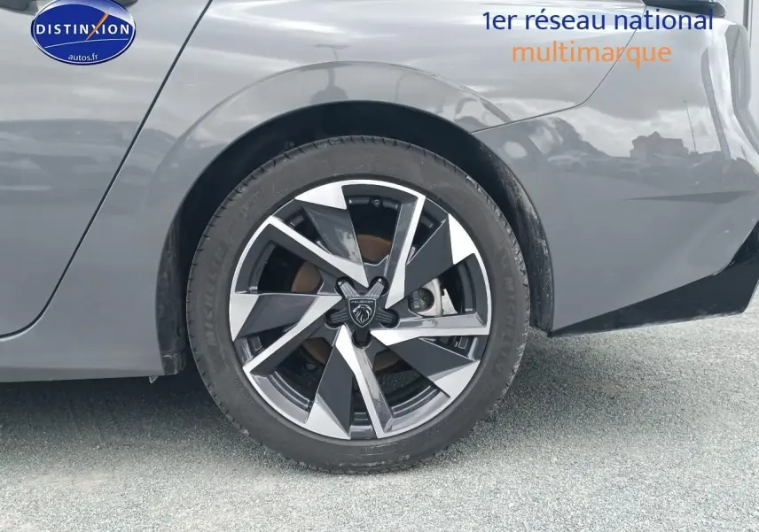 Gros plan sur la roue arrière droite d'une Peugeot 308 SW gris sélénite avec jante alu au design moderne.