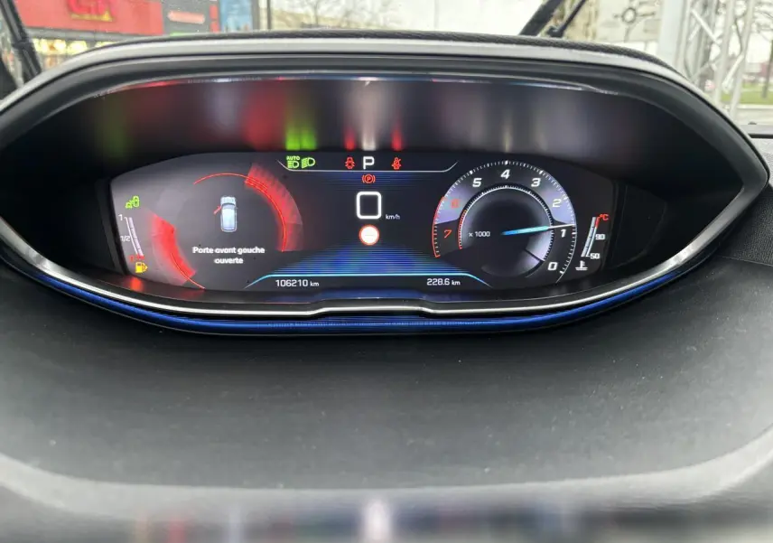 Tableau de bord numérique du Peugeot 3008 blanc, affichant la vitesse à zéro et porte avant gauche ouverte.