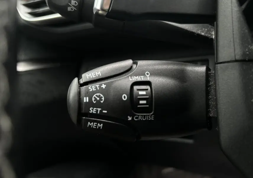 Commande de régulateur de vitesse noir vue en gros plan à gauche du volant d'un Peugeot 3008 blanc de 2018