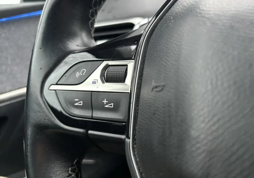 Gros plan sur les commandes gauche du volant noir du Peugeot 3008 blanc nacré de 2018.