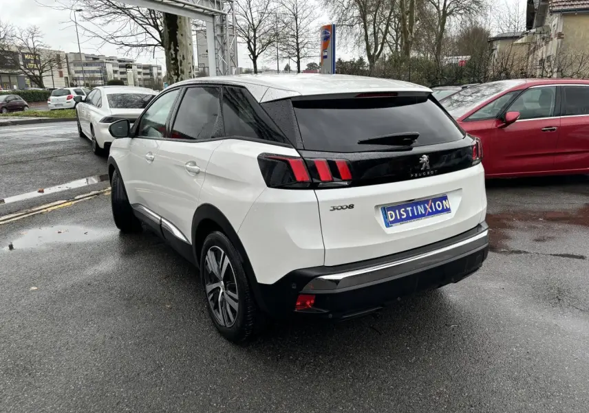 Vue 3/4 arrière droite d'un Peugeot 3008 blanc nacré avec feux arrière à griffes et toit noir.