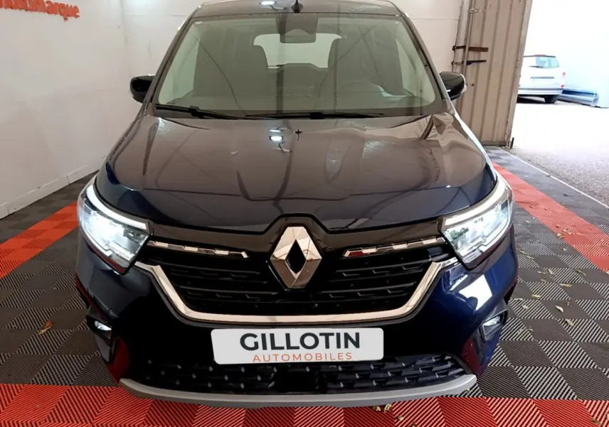 Vue frontale du Renault Kangoo Equilibre TCe 100 bleu 2023 avec calandre noire et phares LED allumés.