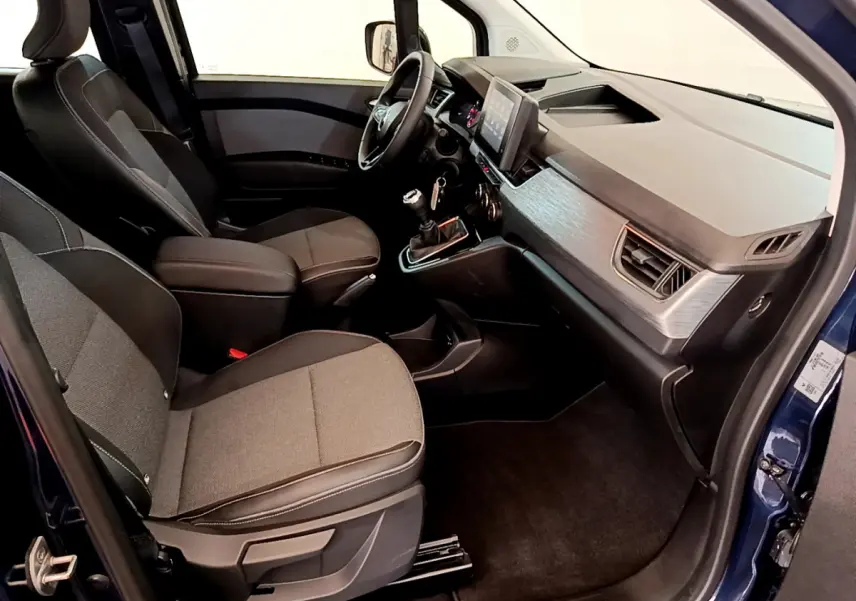 Intérieur avant droit du Renault Kangoo bleu 2023, sièges tissu gris, tableau de bord moderne avec écran tactile central.