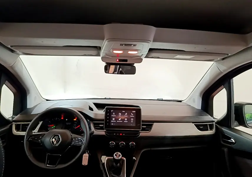 Vue intérieure avant du Renault Kangoo bleu 2023, tableau de bord moderne avec écran tactile central et volant multifonctions.