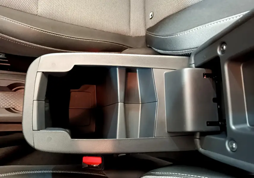 Vue rapprochée de la console centrale ouverte du Renault Kangoo 2023, sièges tissu gris visibles.