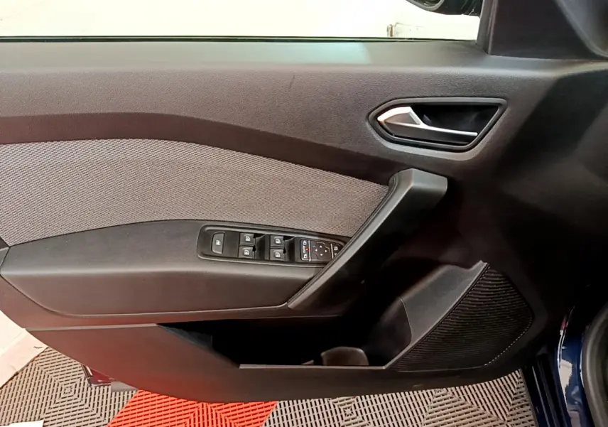 Vue rapprochée de la porte avant gauche du Renault Kangoo bleu 2023 avec commandes de vitres et poignée intégrée.