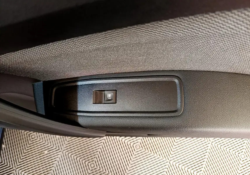Bouton de commande de lève-vitre sur la portière intérieure d’un Renault Kangoo bleu 2023, vue rapprochée.