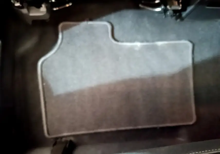 Tapis de sol gris foncé en gros plan sous les pédales du conducteur d'un Renault Kangoo bleu 2023.