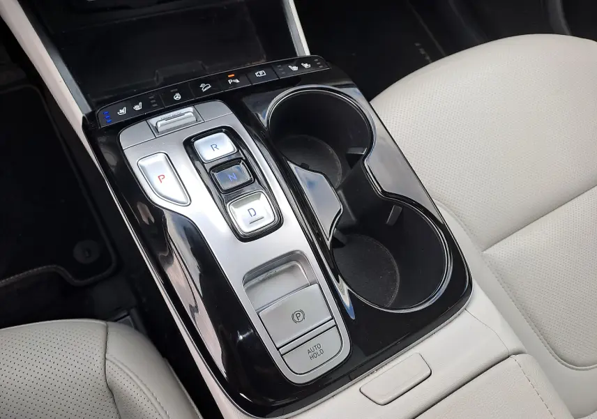 Vue rapprochée de la console centrale noire brillante avec commandes de boîte auto et sièges beige clair du Hyundai Tucson 2023.