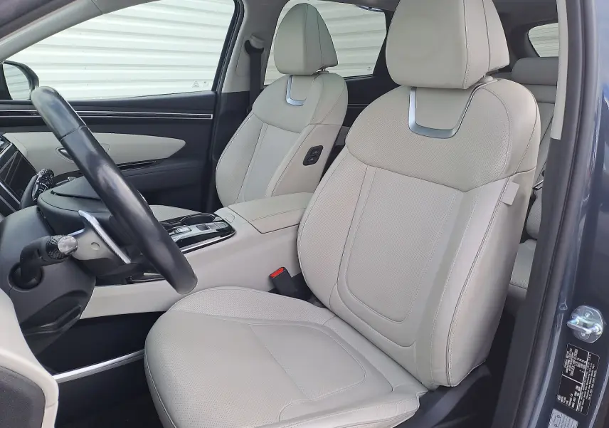 Intérieur du Hyundai Tucson 2023, vue côté conducteur, sièges en cuir beige clair avec finitions métalliques élégantes.