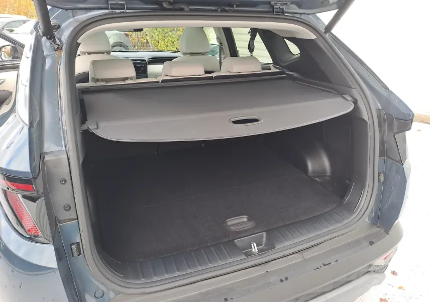 Coffre ouvert en vue arrière d'un Hyundai Tucson Cypress Green 2023 avec cache-bagages et intérieur beige visible.