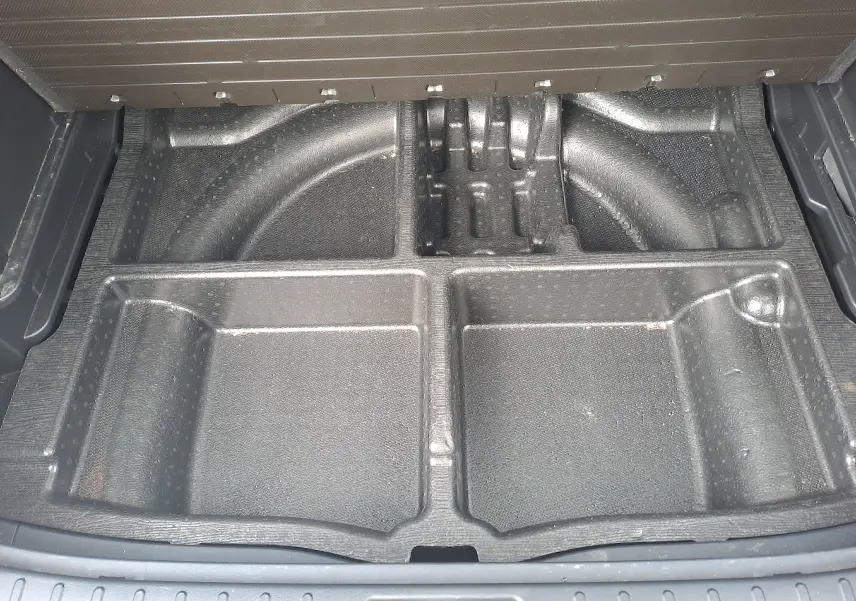 Compartiment de rangement noir sous le plancher du coffre du Hyundai Tucson 2023, version hybride Cypress Green.