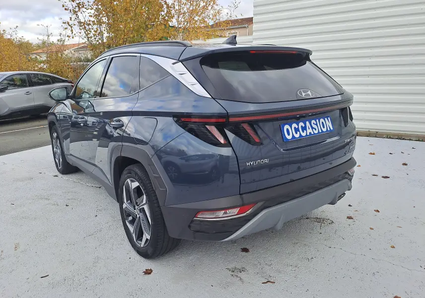 Vue 3/4 arrière droite d'un Hyundai Tucson 2023 bleu foncé avec feux arrière LED et toit noir brillant.