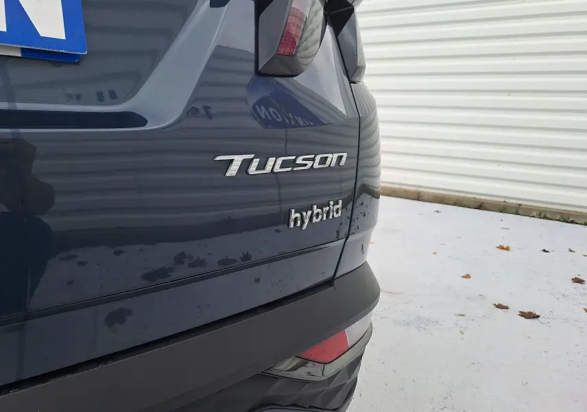 Gros plan sur l'arrière droit du Hyundai Tucson hybride 2023 en Cypress Green avec logo distinctif "Tucson" et "hybrid".