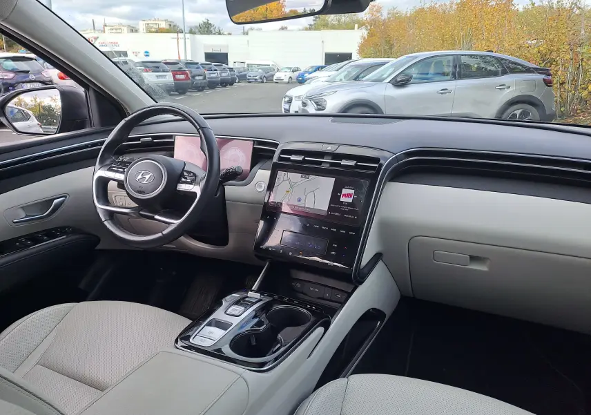 Intérieur beige clair du Hyundai Tucson 2023, vue depuis le siège conducteur sur le tableau de bord et écran tactile central.