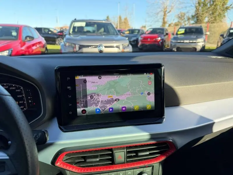 Vue intérieure du tableau de bord de la SEAT Ibiza 2025 avec écran tactile et détails rouges autour des aérateurs.