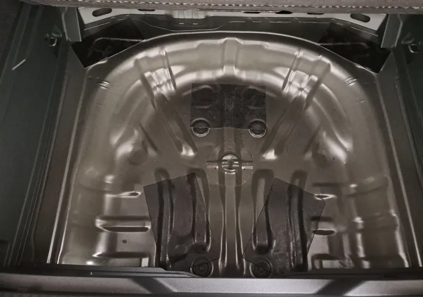 Vue plongeante sur le coffre ouvert du Volkswagen T-Roc 2026 noir, montrant l’espace de rangement sans roue de secours.