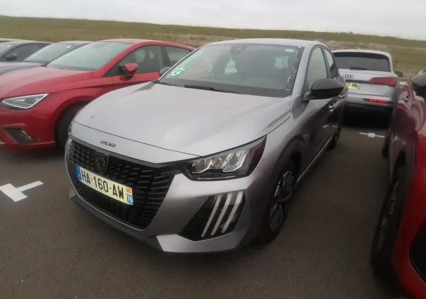 Peugeot 208 gris clair vue 3/4 avant droit avec calandre noire et feux à signature LED 3 griffes.