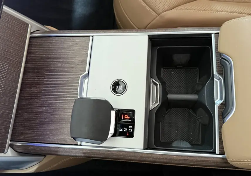 Vue plongeante sur la console centrale bois et aluminium avec levier de vitesse et bouton start/stop du Range Rover noir.