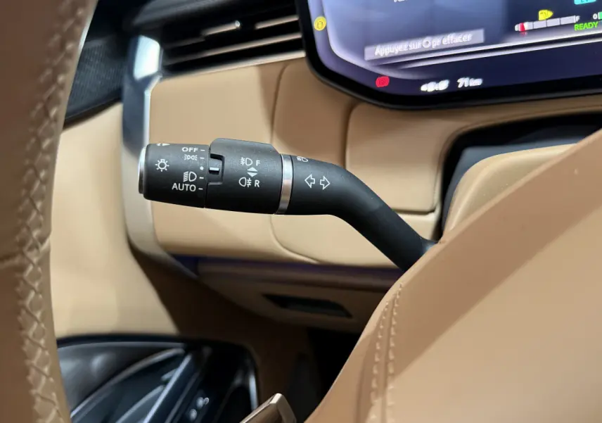 Gros plan sur la commande des feux et clignotants dans l’habitacle beige du Range Rover PHEV 2024 noir.