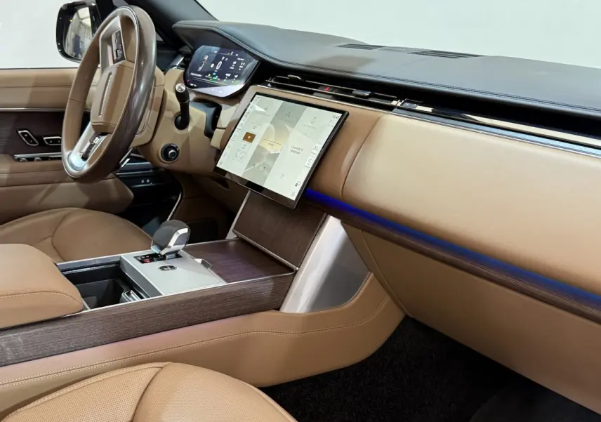 Vue intérieure côté passager du tableau de bord beige et bois du Range Rover PHEV P550e 2024 avec écran tactile central.