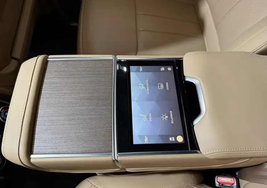 Vue rapprochée de la console centrale beige du Range Rover PHEV 2024 avec écran tactile intégré et finition bois.