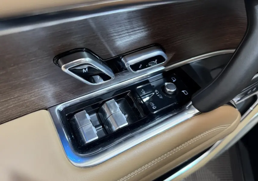Détail des commandes de réglage des sièges et des vitres côté conducteur, garniture bois et cuir beige du Range Rover PHEV 2024.