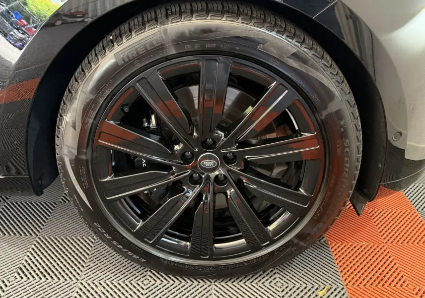 Gros plan sur la roue avant droite noire brillante du Range Rover PHEV P550e 2024 avec jante Land Rover.