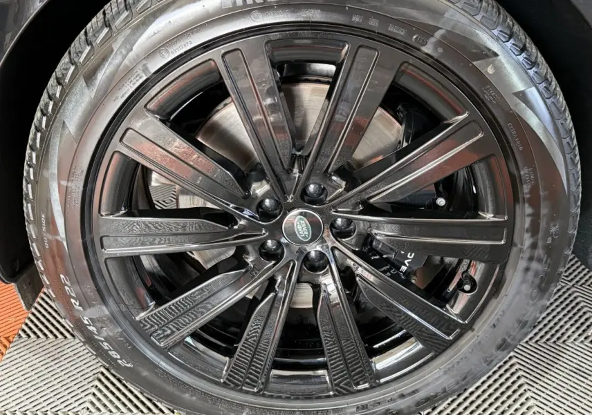 Gros plan sur la jante noire brillante de 22 pouces avec logo Land Rover au centre, montée sur pneu Pirelli.