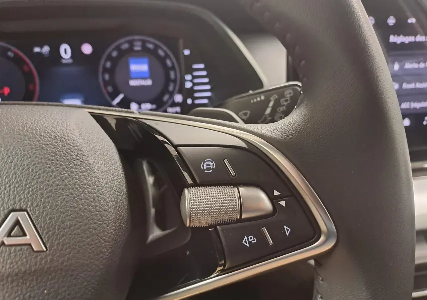 Gros plan sur le volant noir de la Skoda Octavia Combi 2025, montrant les commandes multifonctions avec molette métallique.