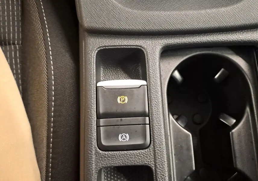 Gros plan sur la console centrale de la Skoda Octavia Combi blanche, montrant les boutons du frein à main électronique et de l'arrêt/start automatique.