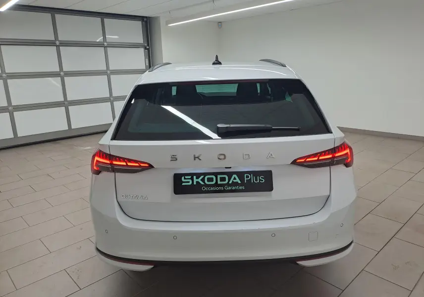 Vue arrière d'une Skoda Octavia Combi blanche Moon avec feux LED allumés dans un garage intérieur.