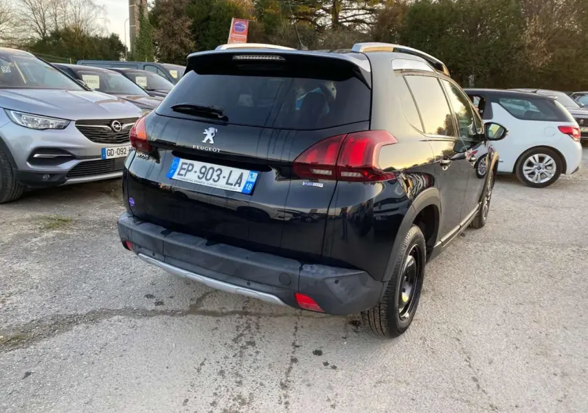 Vue 3/4 arrière droite d'un Peugeot 2008 noir Perla Nera avec feux arrière rouges et toit argenté.