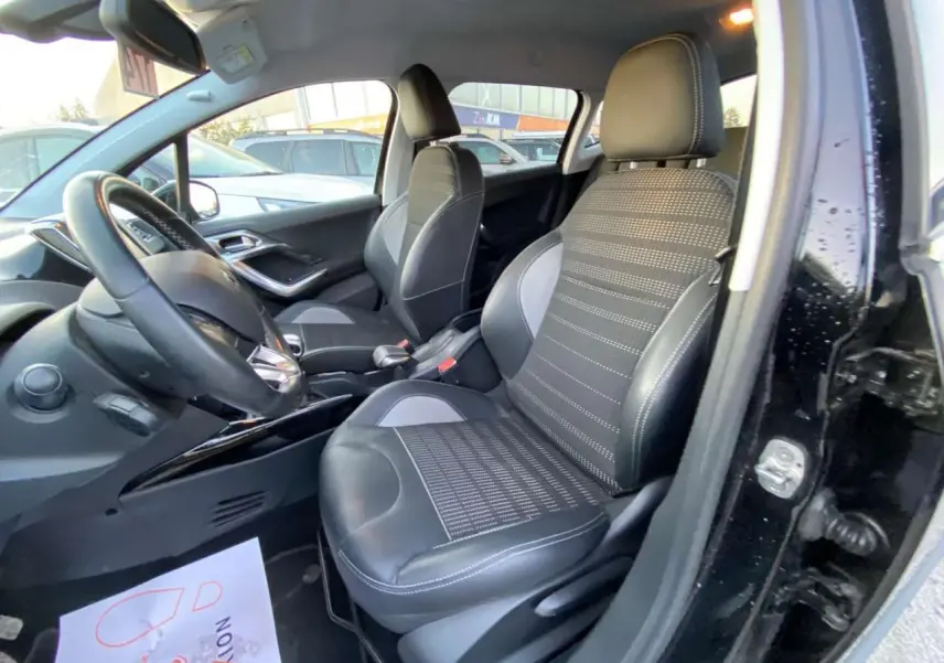 Intérieur côté conducteur d'une Peugeot 2008 noire, sièges sport en tissu et cuir avec coutures contrastées.