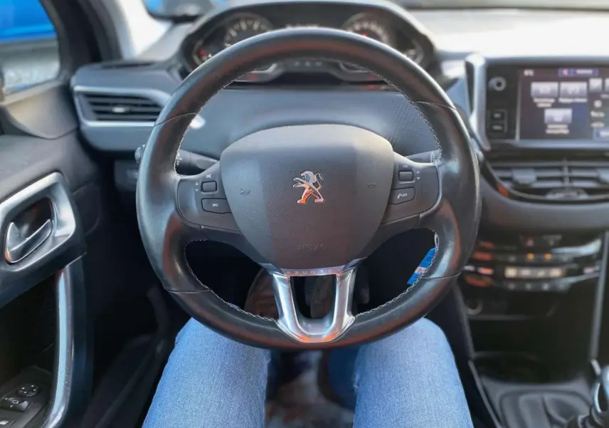 Vue intérieure centrée sur le volant cuir du Peugeot 2008 2017, avec tableau de bord et écran tactile visibles.