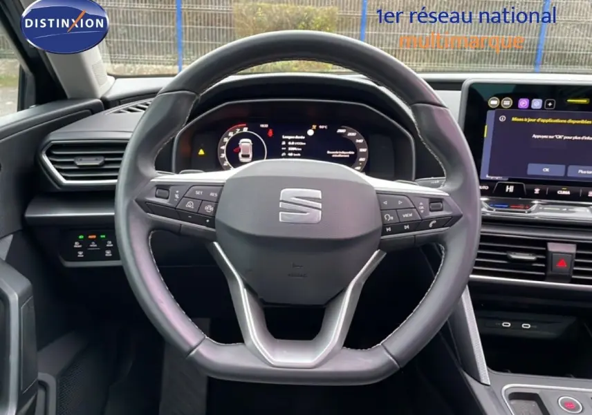 Vue intérieure centrée sur le volant du SEAT Leon IV gris Fiord, avec tableau de bord numérique et écran tactile visible.