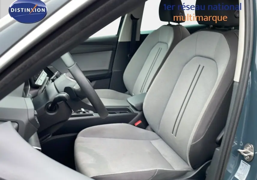 Vue intérieure côté conducteur du SEAT LEON IV 1.5TSI 115 DSG Style 25e Anniversaire avec sièges tissu gris clair.