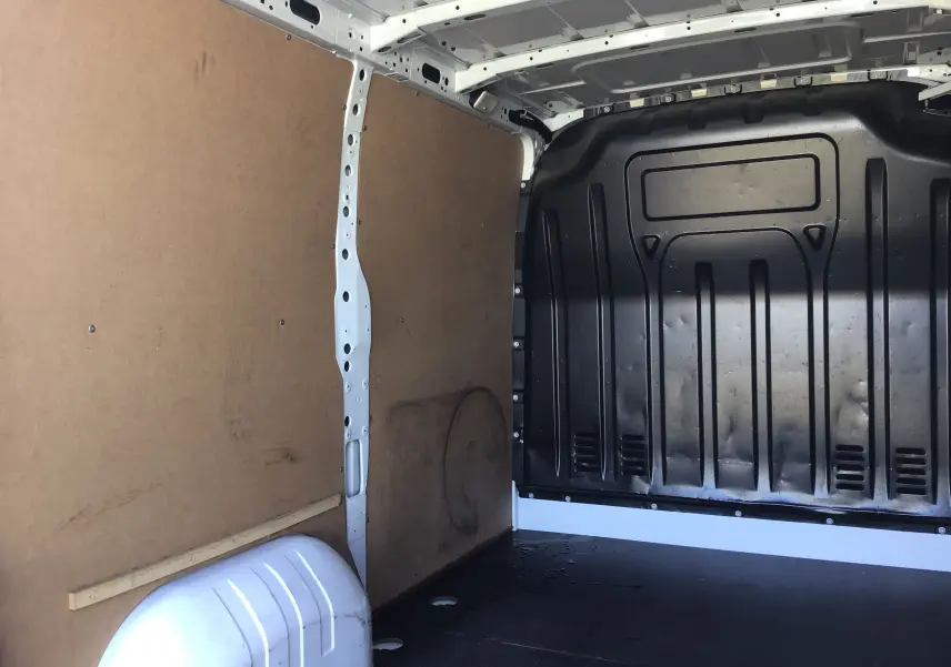 Vue intérieure de la zone de chargement du Renault Master blanc 2023, montrant les parois en bois et la cloison noire arrière.