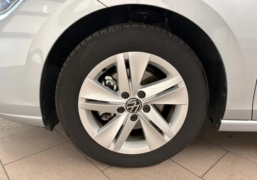Gros plan sur la roue avant droite d'une Volkswagen Golf 2025 reflet d'argent avec jante alliage à cinq branches doubles.
