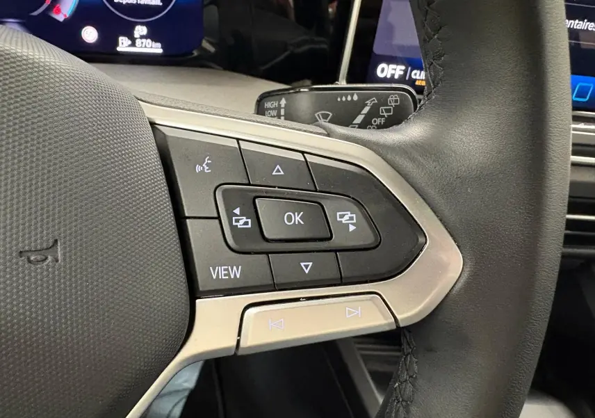 Gros plan sur les commandes multifonctions à gauche du volant noir de la Volkswagen Golf 2.0 TDI 2025 finition Life Plus.