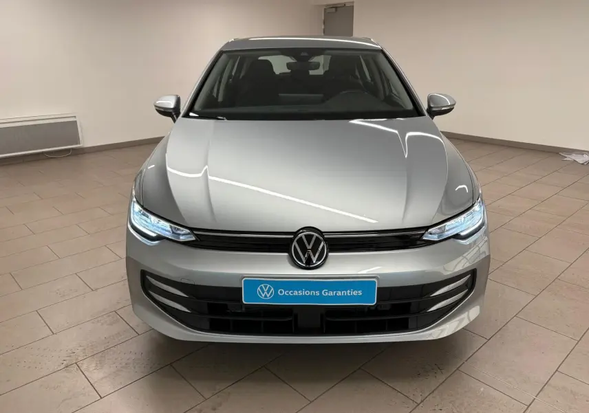 Vue frontale d'une Volkswagen Golf 2.0 TDI 116 BVM6 Life Plus 2025 en reflet d'argent avec phares allumés.